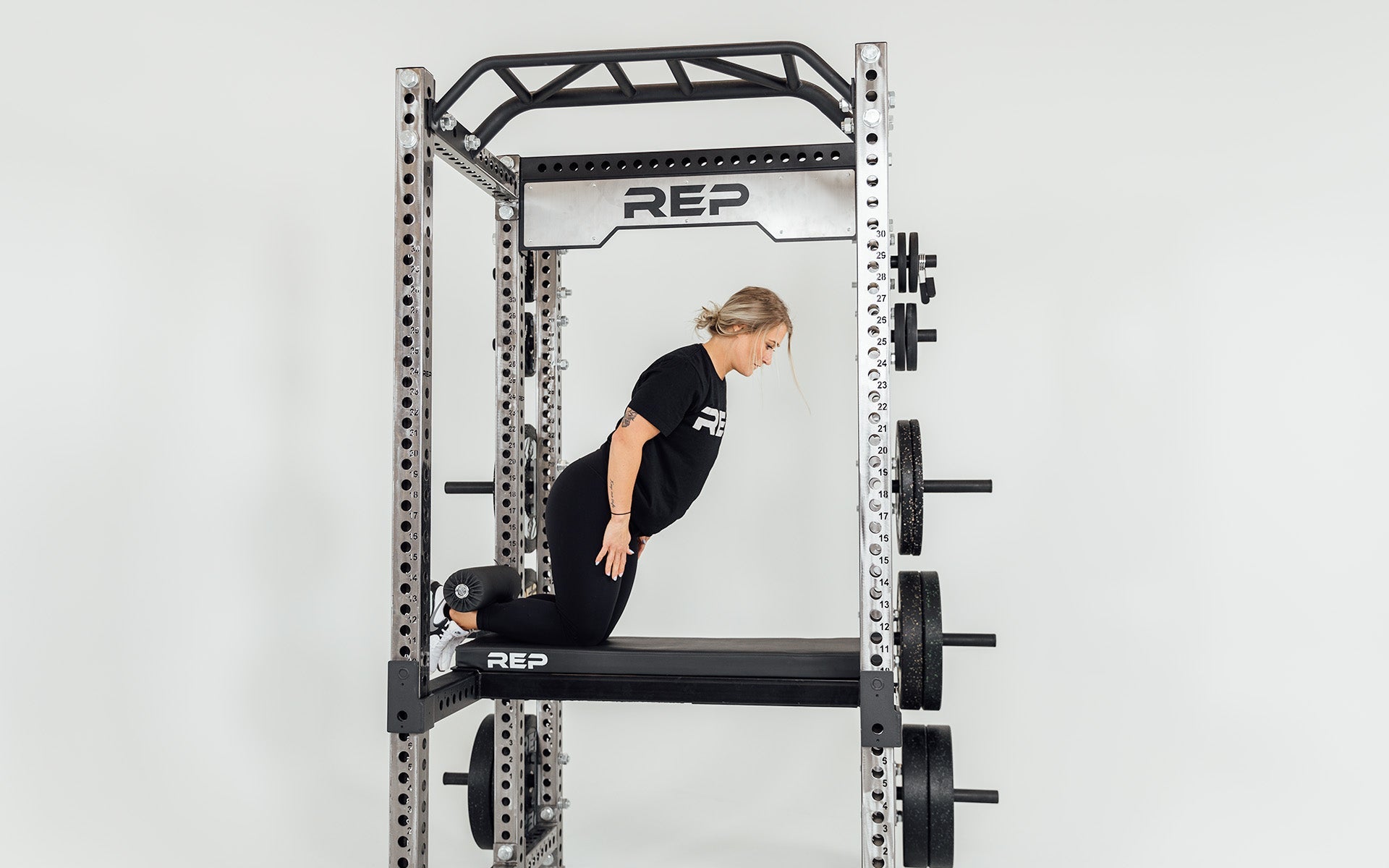Utility Seat + Pad Installed on Flip-Down Safeties on Power Rack Being Used for Nordic Curls